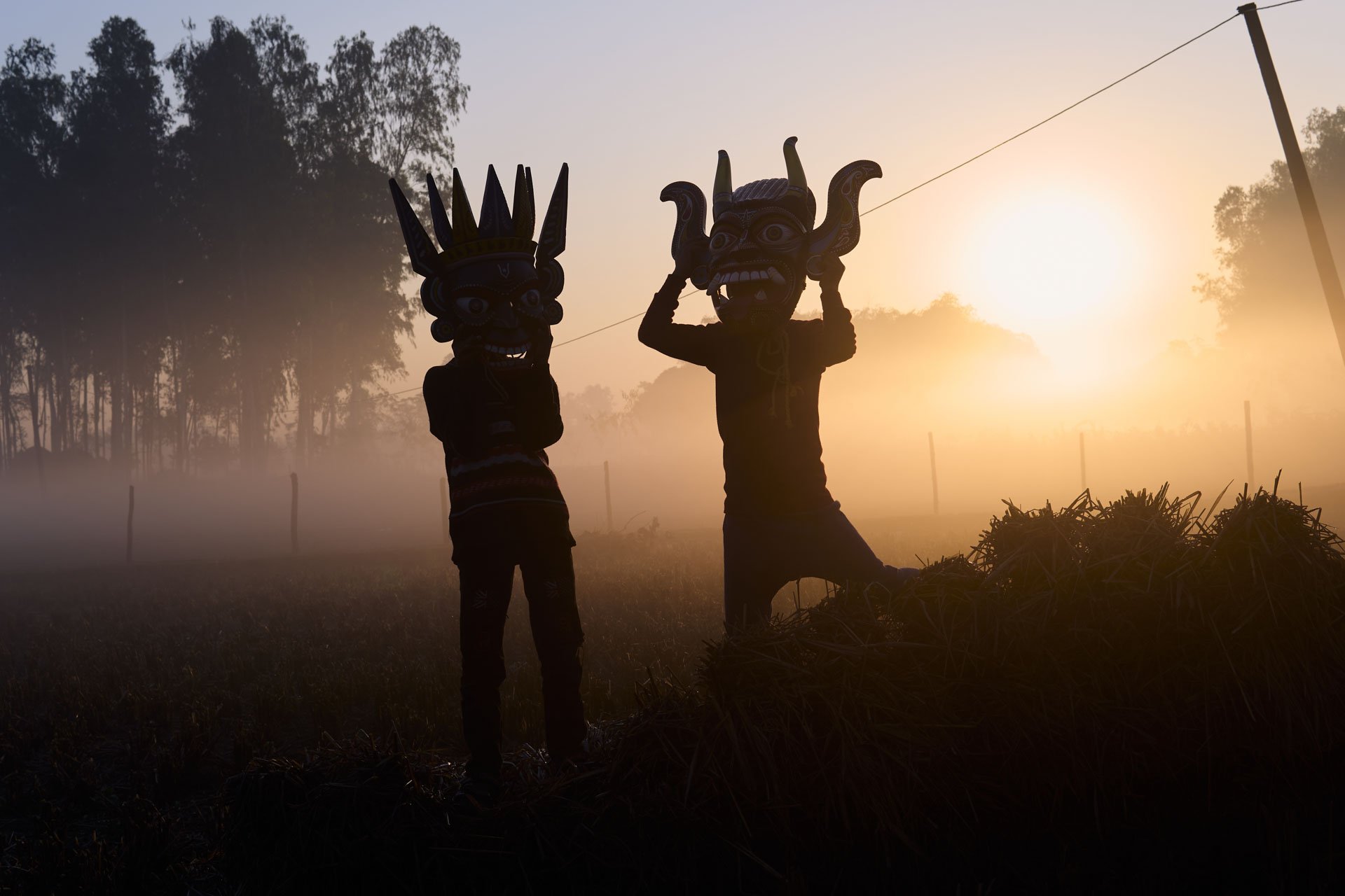 Silhouetted Gomira performers standing together against early morning light.